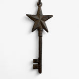 Single cast iron star-topped skeleton key displaying tall silhouette with weathered dark finish