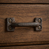 Close-up of dark cast iron drawer pull mounted on a wood drawer front