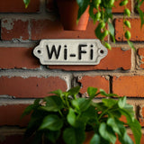 Vintage enamel Wi-Fi sign on red brick wall with weathered cream-white cast iron finish