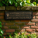 Humorous cast iron office sign reading always arrive late to work but make up for it