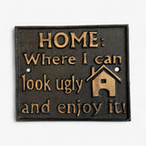 Vintage black cast iron humorous home sign with gold lettering, isolated studio shot