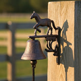 Cast iron horse doorbell with running mare sculpture mounted on wooden gate, rustic bell