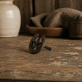Black cast iron horseshoe star cabinet knob with mounting screw on a rustic tabletop