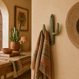 Weathered gold cast iron cactus wall hook holding a striped towel.