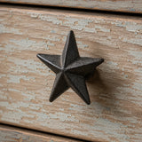 Close-up of black cast iron star cabinet knob on weathered wood drawer front