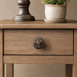 Straight-on view of black cast iron star wheel drawer knob on a wooden cabinet