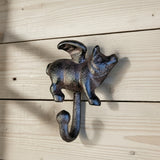 Rustic cast iron flying pig wall hook with patina finish on whitewashed wood