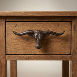 Cast iron longhorn drawer pull centered on a rustic wood drawer front