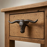 Angled close-up of dark cast iron longhorn cabinet pull on a wood nightstand