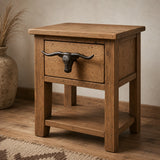 Wood nightstand with cast iron longhorn drawer pull in a rustic room setting