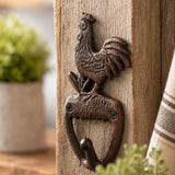 Close-up of cast iron rooster wall hook on weathered wood.