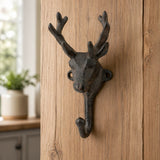 Cast iron deer head wall hook mounted on a wooden panel.