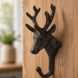 Close-up of a cast iron deer head hook on wood.
