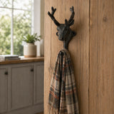 Cast iron deer head wall hook holding a plaid scarf.