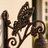Close-up of a cast iron butterfly wall bell and scrollwork.