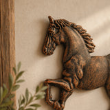 Close view of cast iron running horse wall plaque on beige wall.