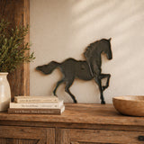 Cast iron running horse wall plaque displayed on a wall above a cabinet.