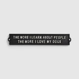 Horizontal black cast iron dog-themed plaque with mounting holes and embossed text on white background