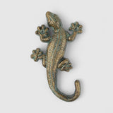 Weathered green and gold cast iron lizard hook showing patina finish with textured surface