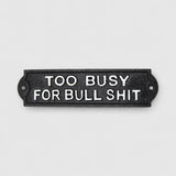 Cast iron too busy for bullshit sign mounted on white painted wooden boards outdoor