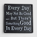 Close-up of black cast iron plaque with motivational quote and mounting holes
