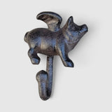 Antique black cast iron pig hook with weathered metallic patina, studio backdrop