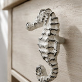 Close-up of distressed white seahorse drawer knob on a textured cabinet front