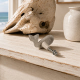 Back view of white whale drawer knob with mounting screw on a distressed tabletop