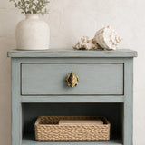 Coastal nightstand with brass sea turtle drawer knob, basket, and shell decor