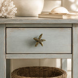 Brass starfish drawer knob centered on a distressed blue coastal nightstand drawer