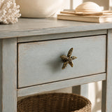 Angled close-up of brass starfish cabinet knob on a weathered blue drawer front