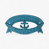 Cast iron Ship Happens sign closeup showing embossed anchor, text, and rustic patina finish