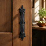 Front view of black cast iron decorative door pull with fleur-de-lis details
