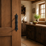 Rustic wood door with black cast iron pull handle in a farmhouse kitchen