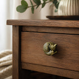 Angled view of brass fox drawer knob on a wooden nightstand