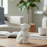 Cream-colored cast iron bunny statue with tall ears displayed on wooden surface in home interior setting