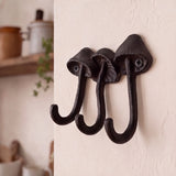 Close angled view of dark black-brown cast iron mushroom wall hooks with three curved hooks, SKU GB78067