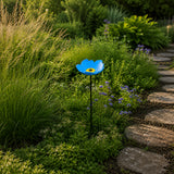 Blue cast iron flower bird feeder and bath among green garden plants.