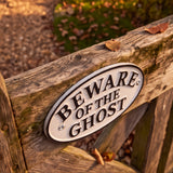 Angled view of oval Beware of the Ghost cast iron sign with visible screws, SKU GB78095