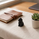 Small black cast iron puppy paperweight beside a leather notebook, SKU GB78103