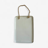 Cream-colored cast iron welcome sign back view, blank reverse side with rope hanger attachment