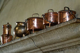 Brass and copper pots on a rustic stone shelf