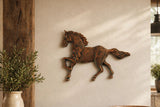 Cast iron running horse wall plaque hung on a cream wall beside a rustic wood post