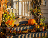 Front porch steps decorated for fall with pumpkins, gourds, and autumn leaves in evening light