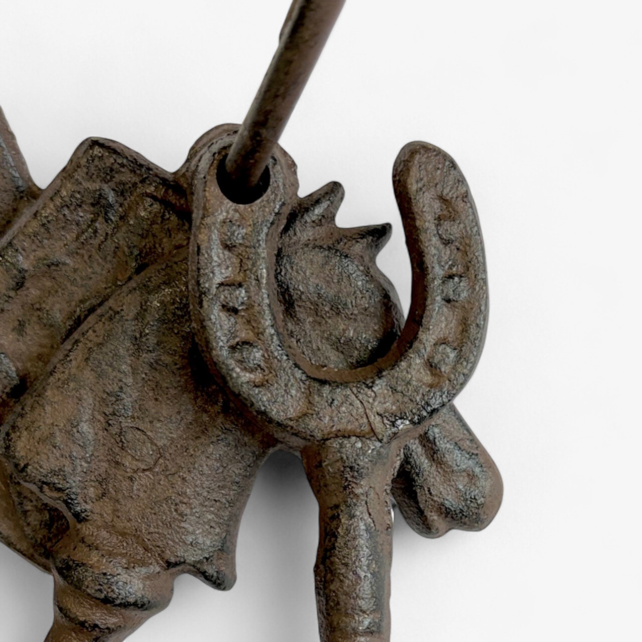 Side view of decorative horse head charm with weathered cast iron finish and textured surface
