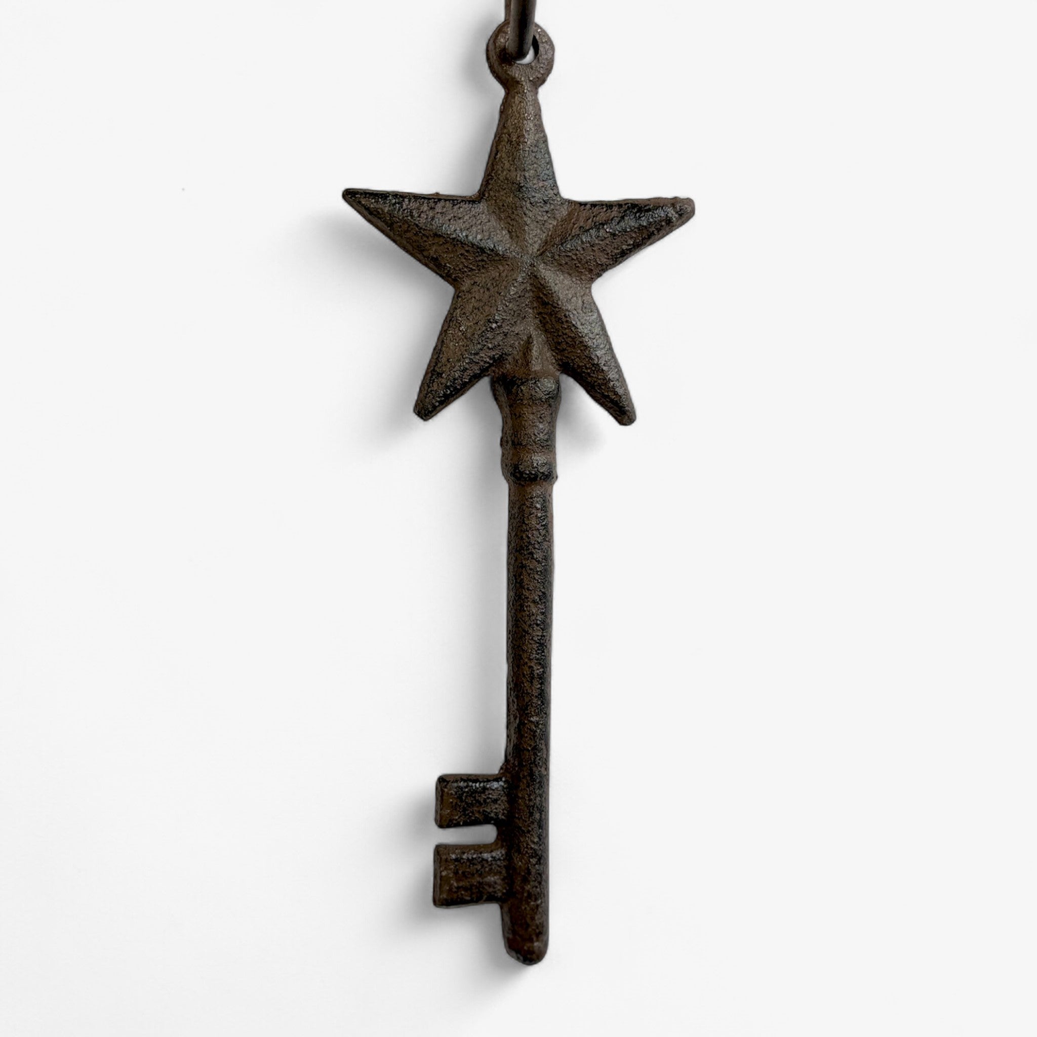 Single cast iron star-topped skeleton key displaying tall silhouette with weathered dark finish