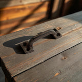 Antique cast iron drawer pull handle on weathered wood with rustic patina finish