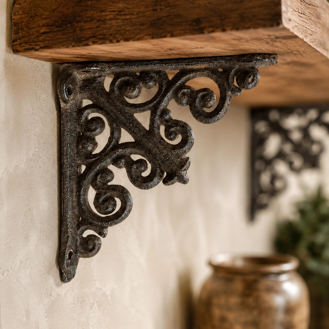 Close-up of ornate black cast iron shelf bracket supporting a rustic wood shelf