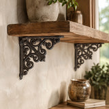 Angled view of black cast iron scrollwork shelf brackets under a wooden wall shelf