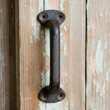Cast iron drawer pull with mounting hardware, dark textured finish on weathered wood cabinet